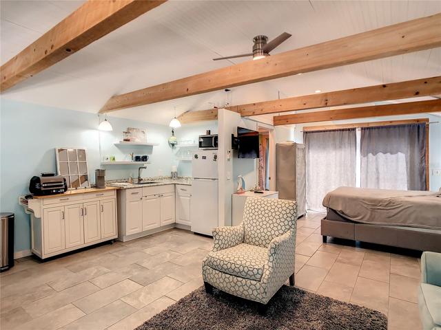 Studio cottage- being sold fully furnished. Entry door is just past this pull out sofa on your right, before the bed. The bath is behind the fridge. Behind the curtains are sliding glass doors leading to a small enclosed patio. Although this space is just around 430 Sf, it feels bigger due to the high ceilings.