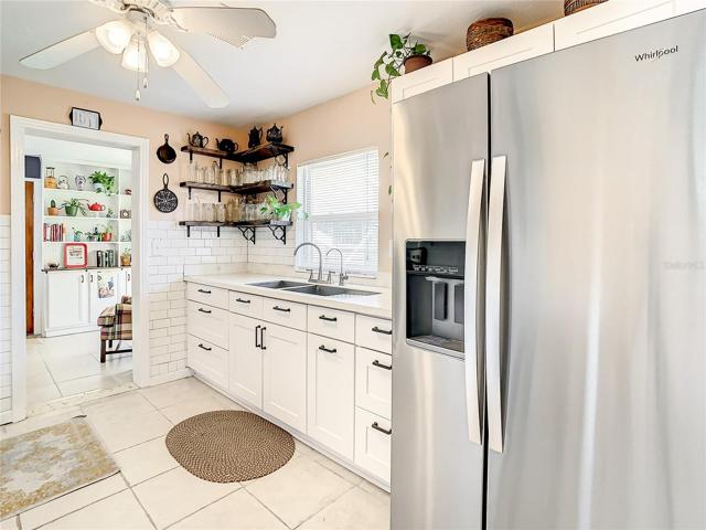 kitchen has been tastefully updated with white shaker-style cabinets, stainless-steel appliances, quartz countertops, modern open shelving, and subway tile backsplash. The kitchen extends to an eat-in breakfast nook furnished with a long built-in bench that maximizes space and seating while providing storage space underneath