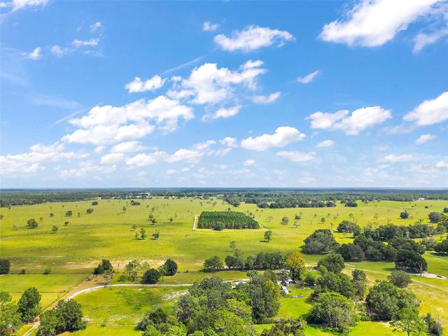 Aerial - from Westside entrance of property looking East. Driveway is on bottom left of photo, turning upward right. Home Roof is visible in center amongst the trees.