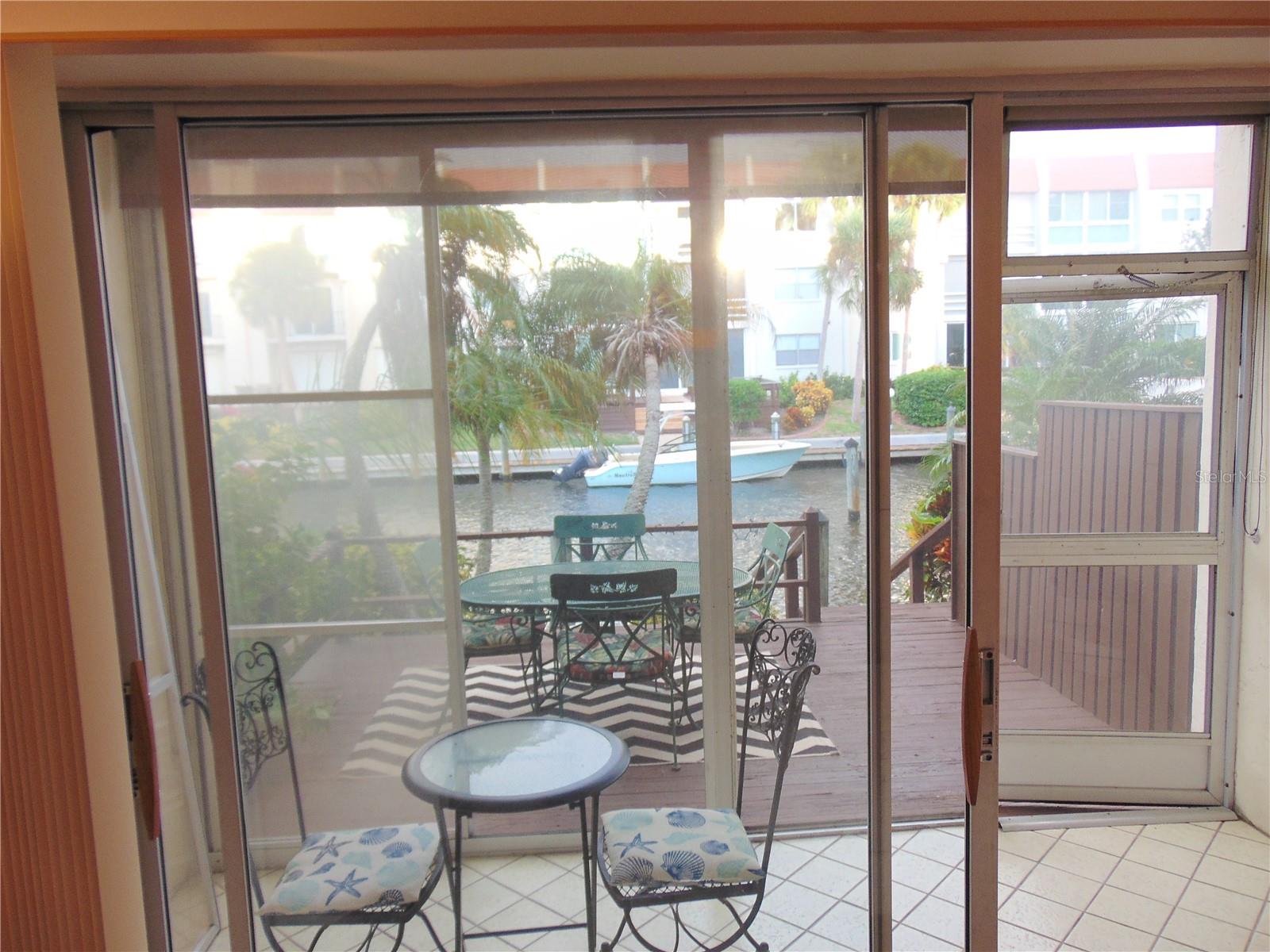 Screened lanai with removable vinyl windows, then the outside deck and canal/lagoon.