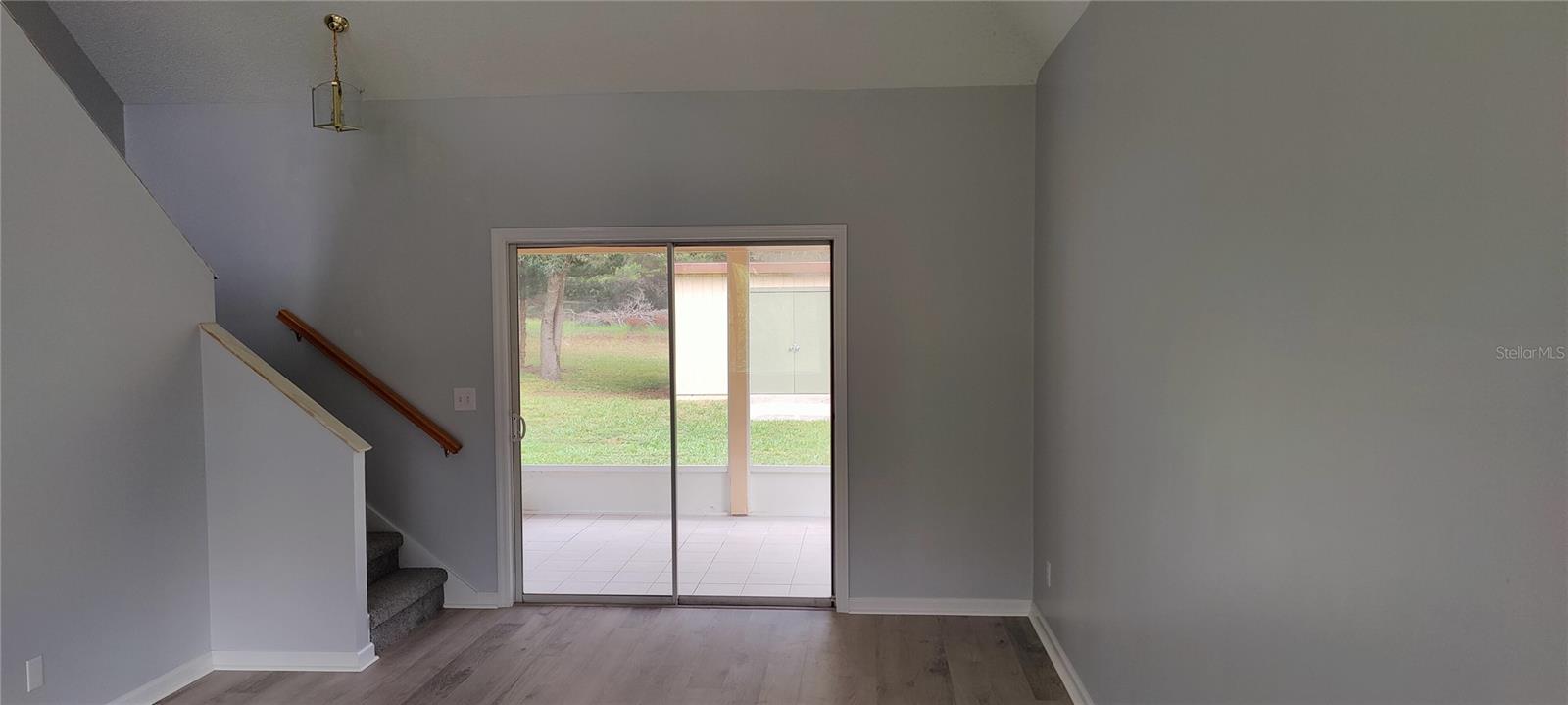 Spacious living room has a two story high cathedral ceiling, New luxury vinyl plank flooring and new rug on stairs has just been installed.  Entire inside and outside of the home was just painted as well.  Sliding patio doors lead to the screened lanai and the back yard.