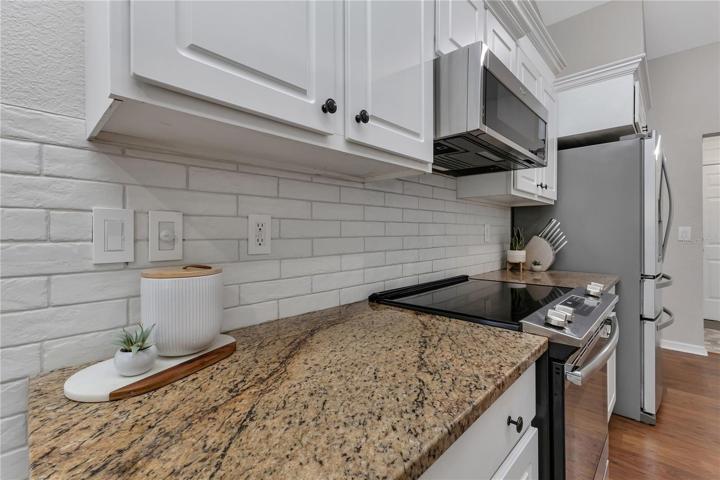 Granite countertops and timeless brick-look Italian tile backsplash