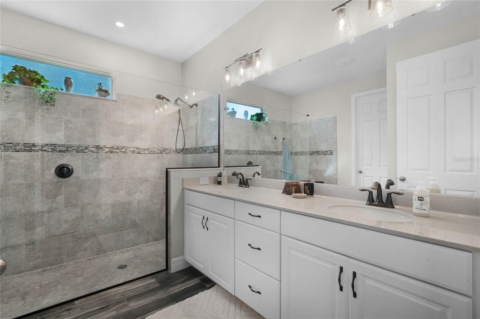Dual sink vanity and frameless glass shower.