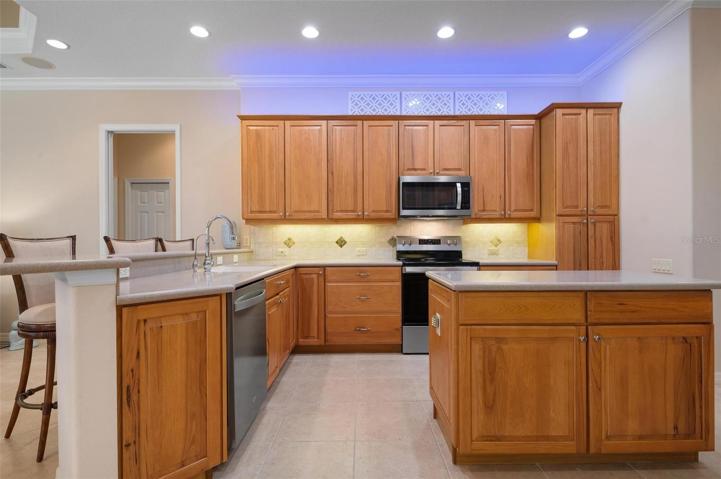 Kitchen with solid wood cabinets, decorative lighting and stainless steel appliances