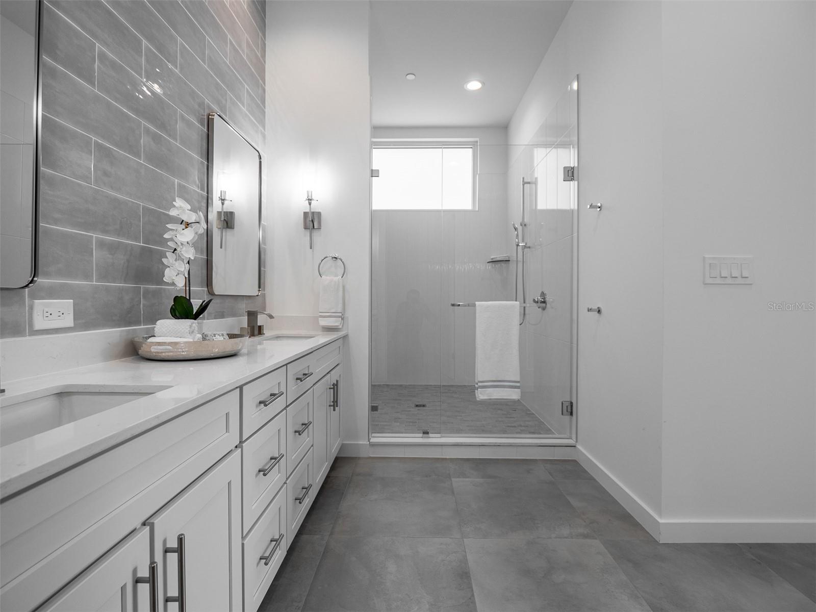 Inviting Primary suite bathroom with double vanities and large shower