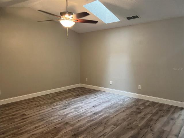 nice open living room area with skylight, ceiling fan and new laminate flooring