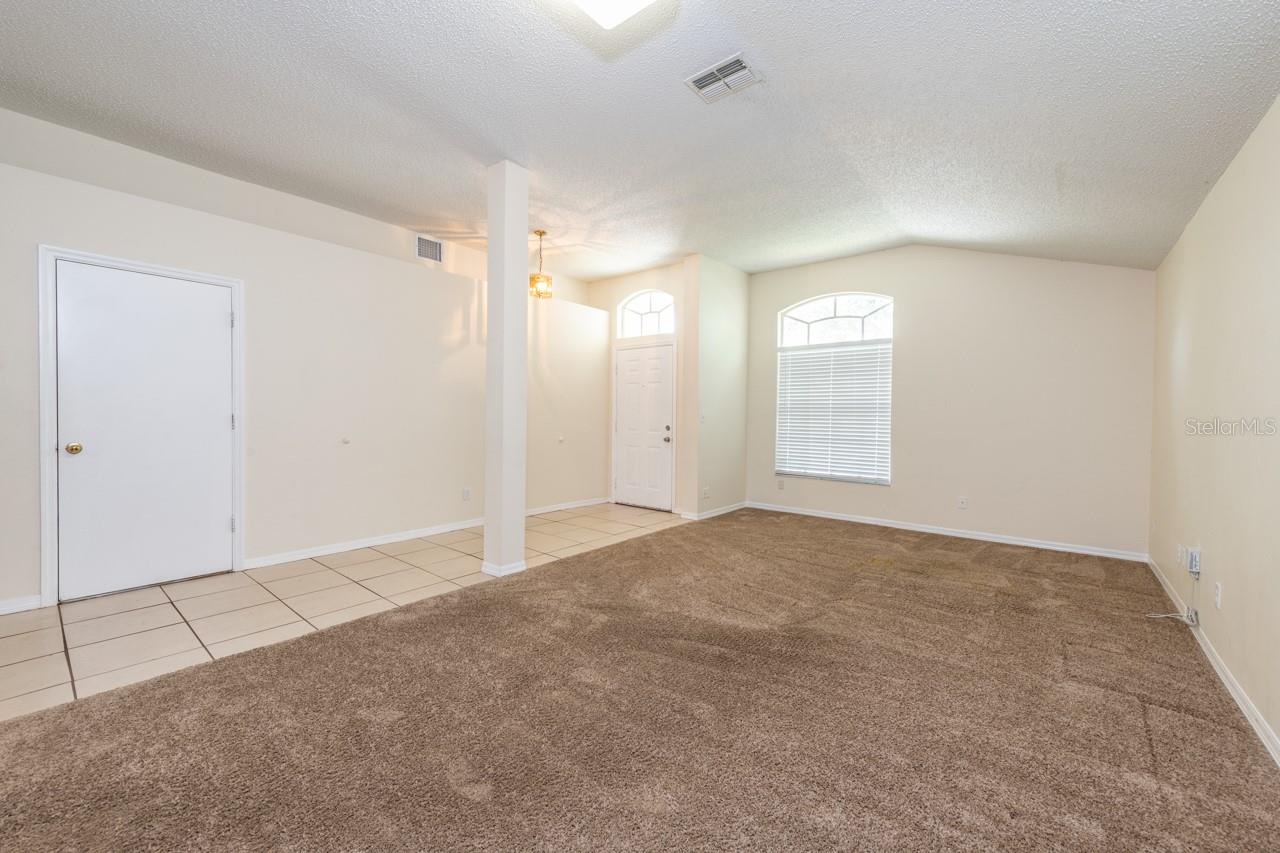 The entryway is tiled into the main part of the home. The carpeted area is formal living/dining.