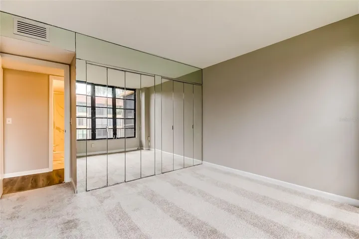 Bedroom #2 with mirrored bifold doors to closet and 2nd bath across hallway