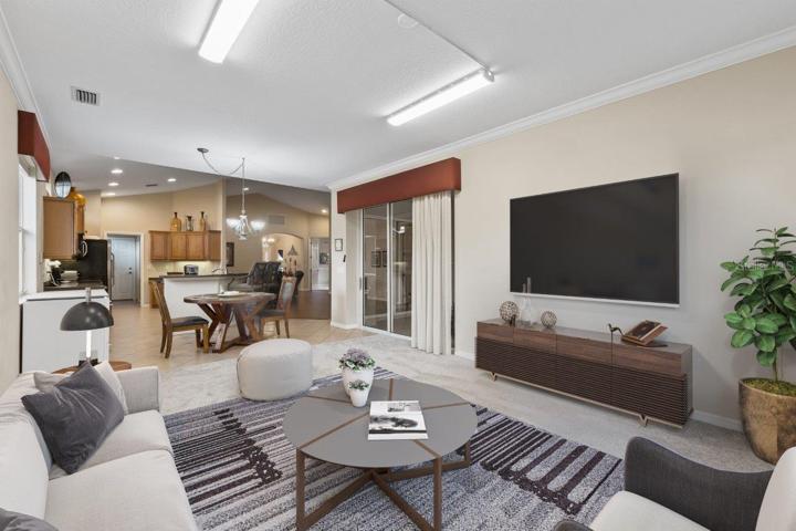 Spacious Family room with crown molding, new carpet, a large window with preserve views, and a sliding glass door to the back lanai and heated pool.