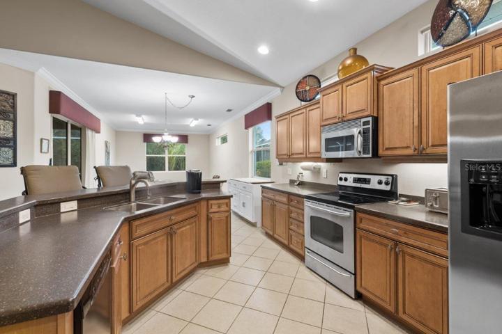 Gourmet Kitchen featuring wood cabinetry, stainless steel appliances, a built-in work station, and large breakfast bar.