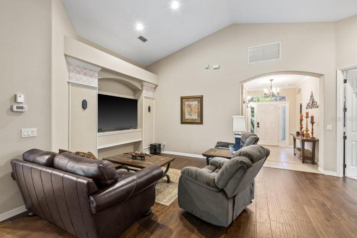 Living room featuring engineered hardwood, cathedral ceilings, and built-in accents.