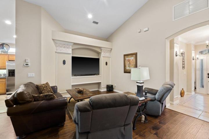 Living room featuring engineered hardwood, cathedral ceilings, and built-in accents.