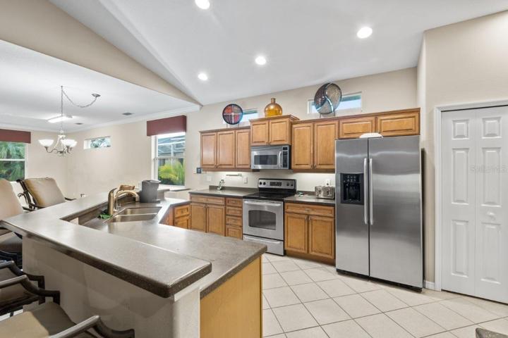 Gourmet Kitchen featuring wood cabinetry, stainless steel appliances, a built-in work station, and large breakfast bar.
