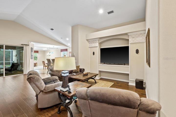 Living room featuring engineered hardwood, cathedral ceilings, and built-in accents.
