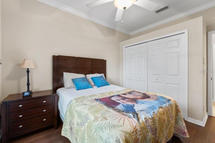 Guest bedroom #2 featuring engineered hardwood, crown molding, and a built-in closet