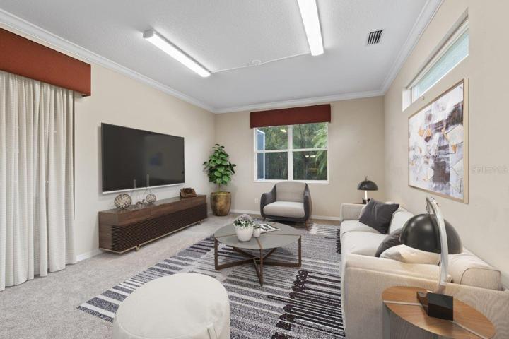 Spacious Family room with crown molding, new carpet, a large window with preserve views, and a sliding glass door to the back lanai and heated pool.