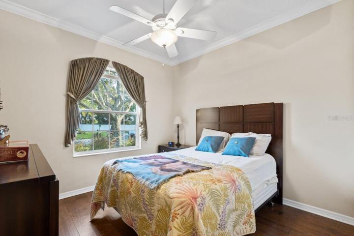 Guest bedroom #2 featuring engineered hardwood, crown molding, and a built-in closet