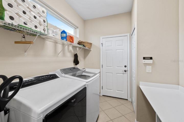 Laundry room off the kitchen featuring a built-in counter/work station