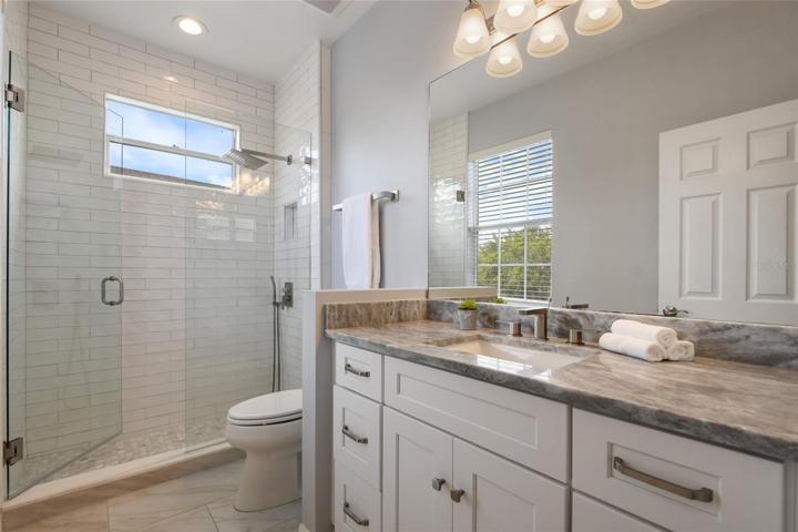 Bathroom 4 attached to the guest room has floor to ceiling shower tile, new vanity, 8