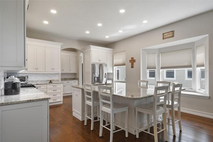 Completely renovated gourmet kitchen in 2021 with stone counter tops throughout accented by under cabinet lighting, back splash, crown molding and stainless steel appliances.