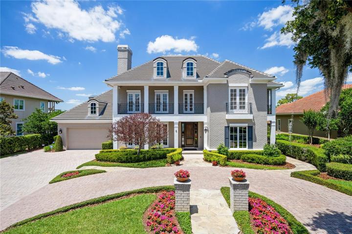 Front elevation...featuring Charleston style double stacked porch, brick paver circular drive, extra-wide driveway with parking pad, and professional landscaping.