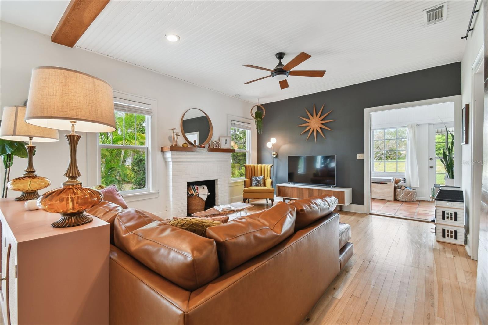 Large, comfortable living room, featuring high wainscoted ceilings accented with wood beams and recessed lighting.