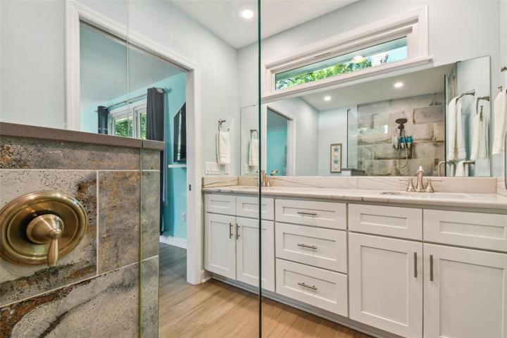 Primary bath with solid wood cabinetry, double vanity and large walk-in shower.  Lifeproof bamboo flooring continues from primary bedroom