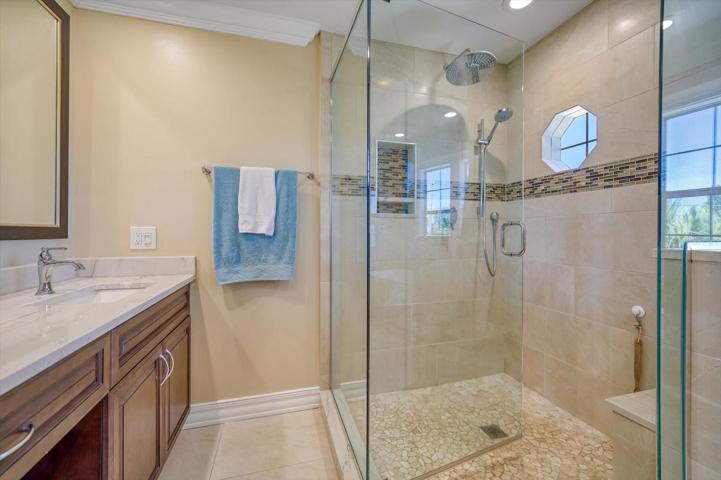 Walk in shower with detailed tile work and port hole adds interest to this area.