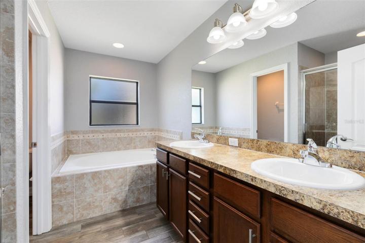 The en suite bathroom exudes a spa-like ambiance with its double vanity, luxurious garden tub, and a separate shower - an inviting space to unwind after a long day.