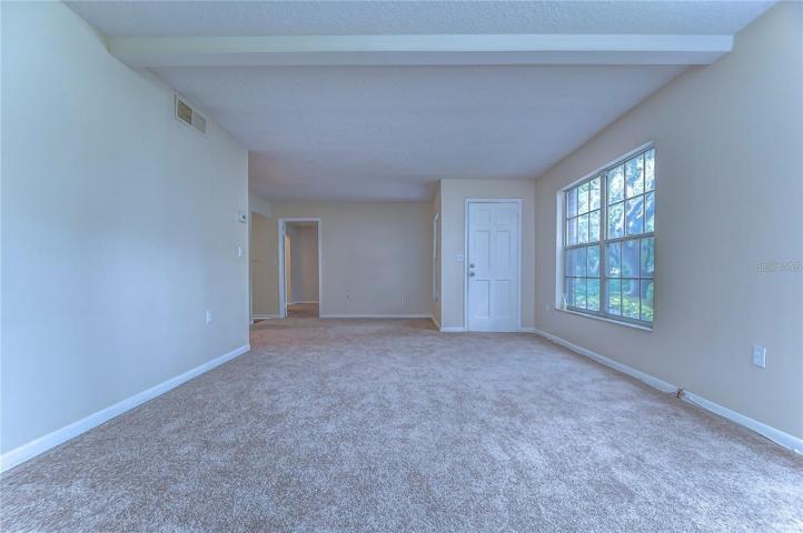 View of living room /dining space & door for back entry (covered porch outside - access to parking area)