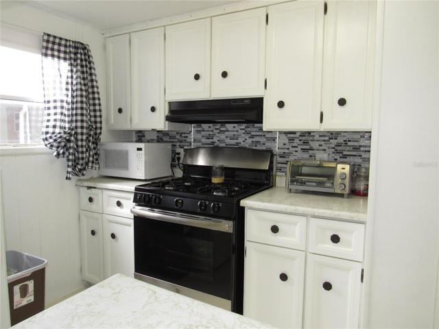 Kitchen with gas stove & vent hood.