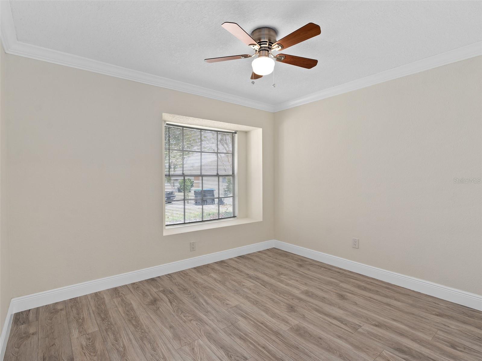 bedroom 2 with luxury vinyl plank flooring. Ceiling fan and crown molding.
