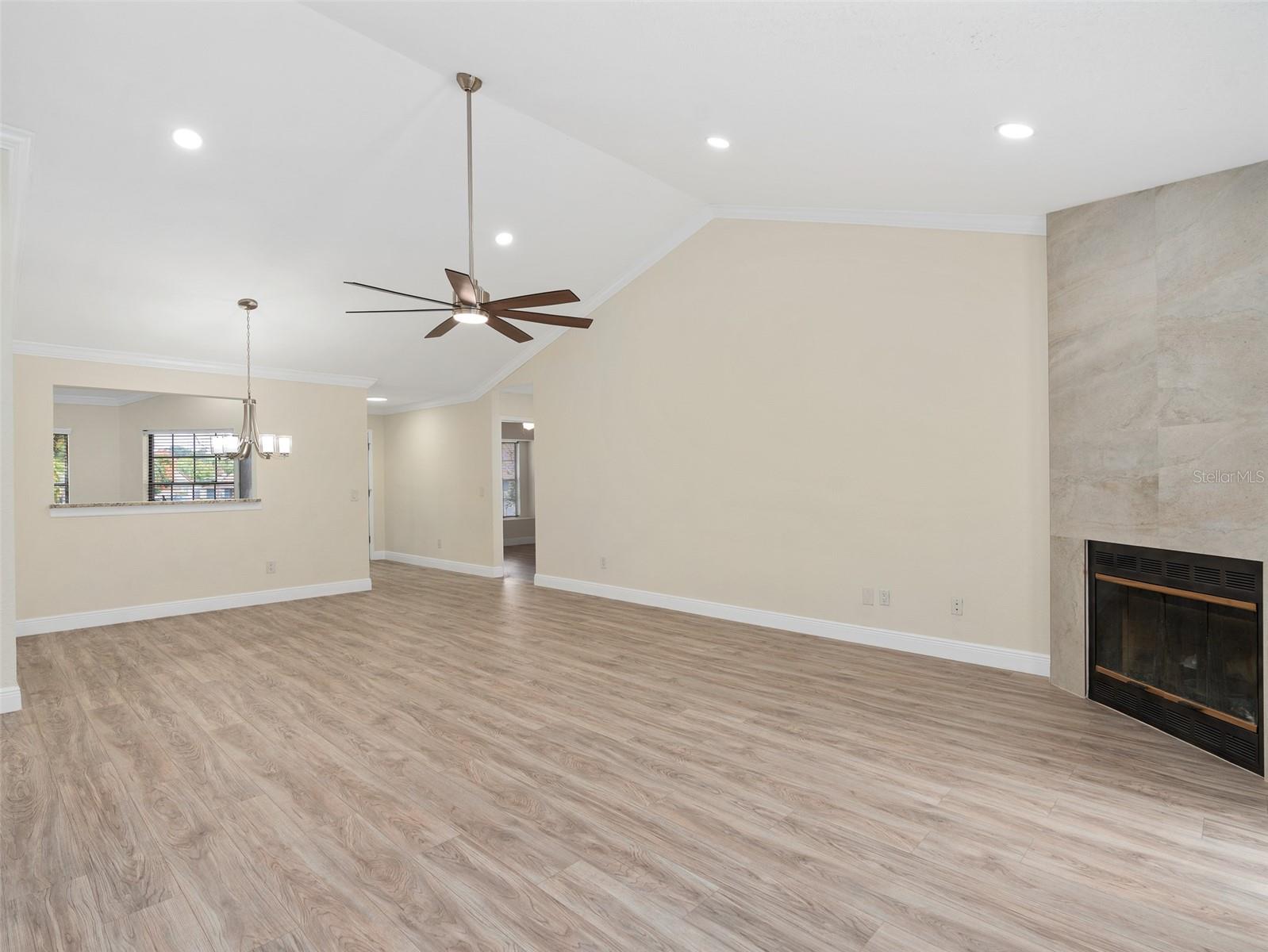 great room with fireplace and new luxury vinyl plank flooring, crown molding, recessed led lighting, redone fireplace backsplash, new paint and upgraded baseboard.