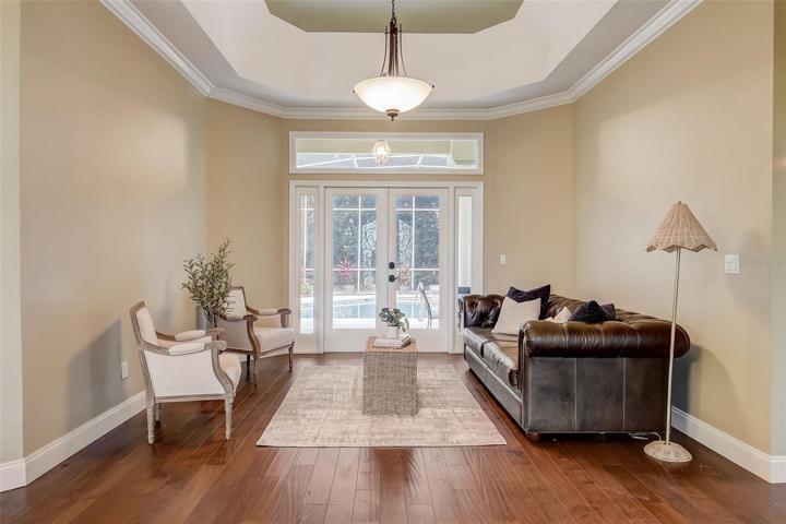 Formal living room with trey ceiling & french doors to the pool deck.