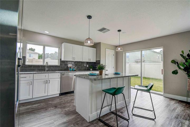 Breakfast bar/island for added storage and open view leading to sliding glass doors and backyard.