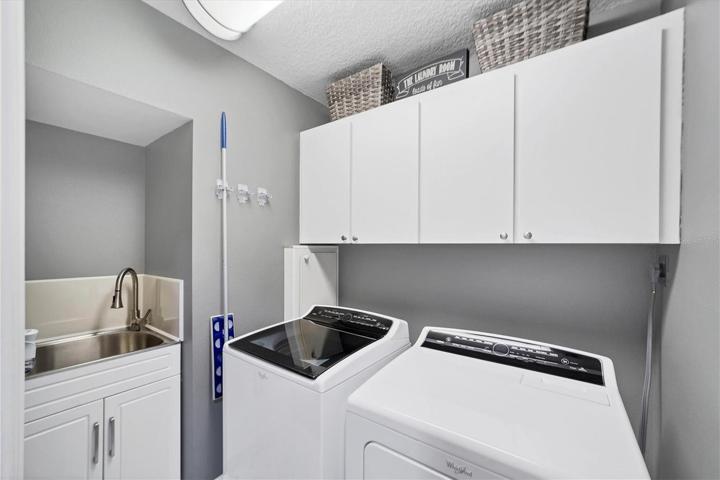 Laundry room has cabinets and utility sink