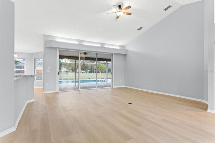 Living room with vaulted ceilings & pool view with large 3 door patio access