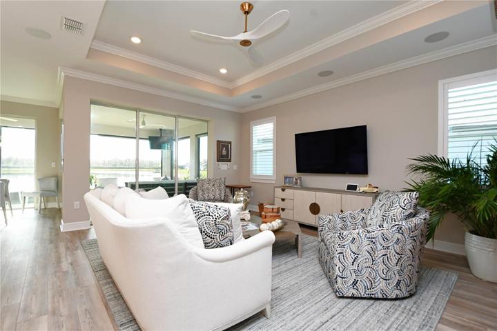 The great room, a symphony of luxury vinyl flooring and a tray ceiling leads out to a screened-in porch, where sunsets paint the sky over tranquil waters.