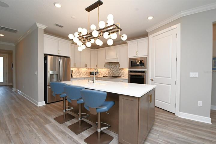 Undercount lighting illuminates the Quartz surfaces, and an artful glass tile backsplash sets the stage for the stainless-steel suite of appliances, including  includes a 5 burner Whirlpool gas cooktop, a French door refrigerator freezer with water dispenser and ice maker, a dishwasher, a Built-in kitchen aide convection oven, and a Whirlpool microwave.