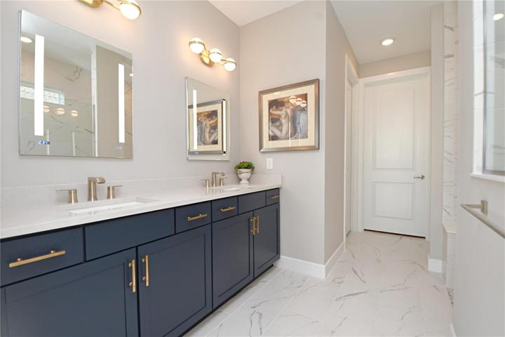 Elegant light fixture and defogging backlit mirror medicine cabinets illuminate this spa-like ensuite