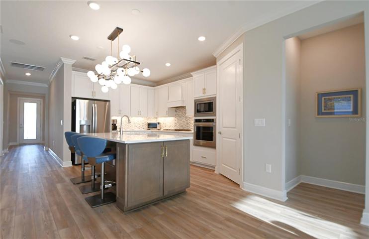 Culinary dreams awaken in the state-of-the-art kitchen, a masterpiece of soft-close wood cabinets in Alabaster hues, with gold-tone hardware.