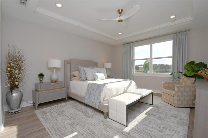 The primary bedroom, a 14’ X 16’ haven with an ensuite bath that rivals a high-end spa. Dual sinks nestle in a navy vanity, accented with gold and lit by decorative fixtures.