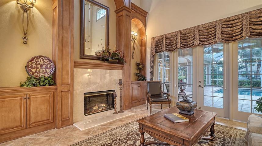 The inviting living room with fireplace, rich maple built-ins and French doors that open to the relaxing pool.