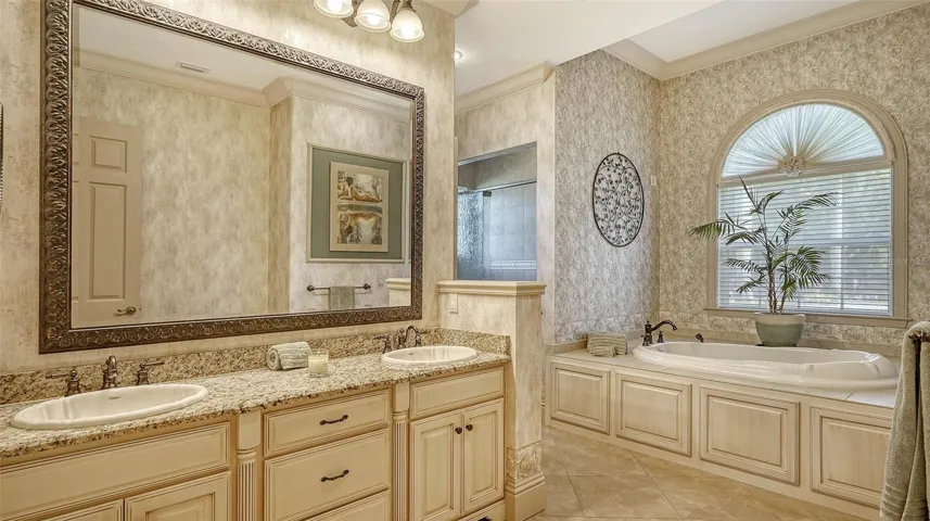 The large first floor owner's suite bathroom with luxe tile and glass spa-like bath.