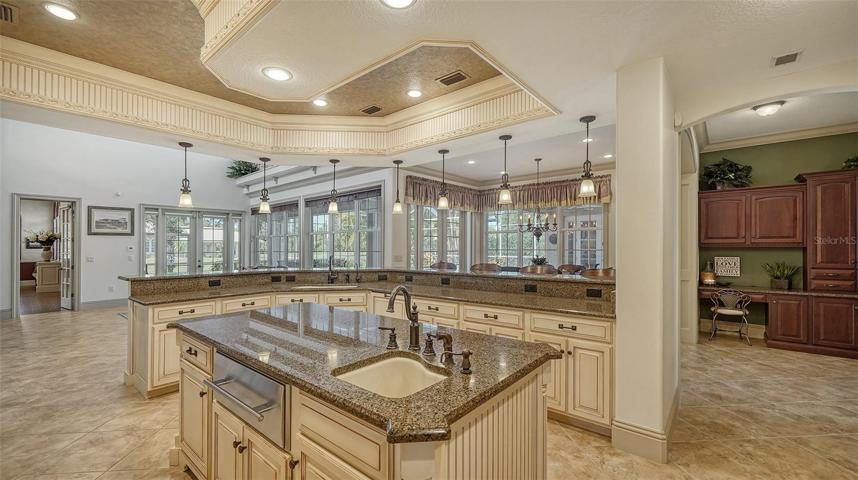 Onto the deluxe chef’s kitchen with spacious L-shaped island, cream colored all wood cabinetry with exquisite millwork by Campbell Cabinetry, and planning desk.