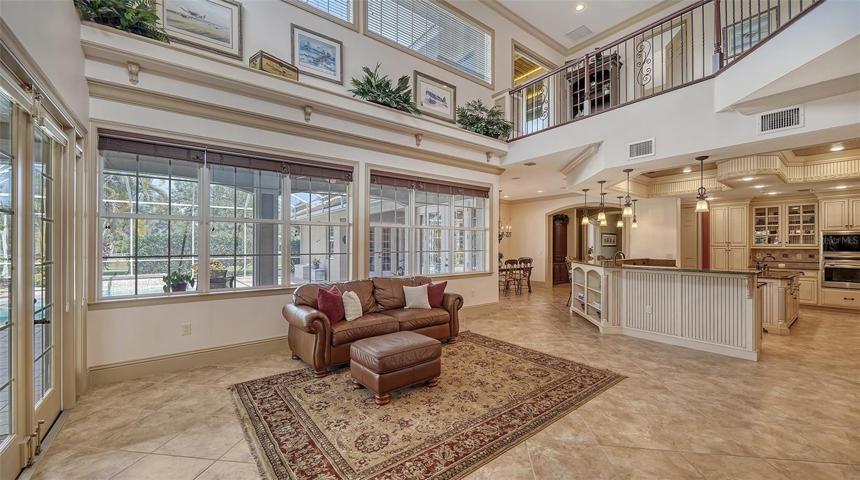 The vast Great Room basks in natural light from above topped by a 22’ ceiling, glass front, solid wood built ins, and French doors leading to more outdoor space.