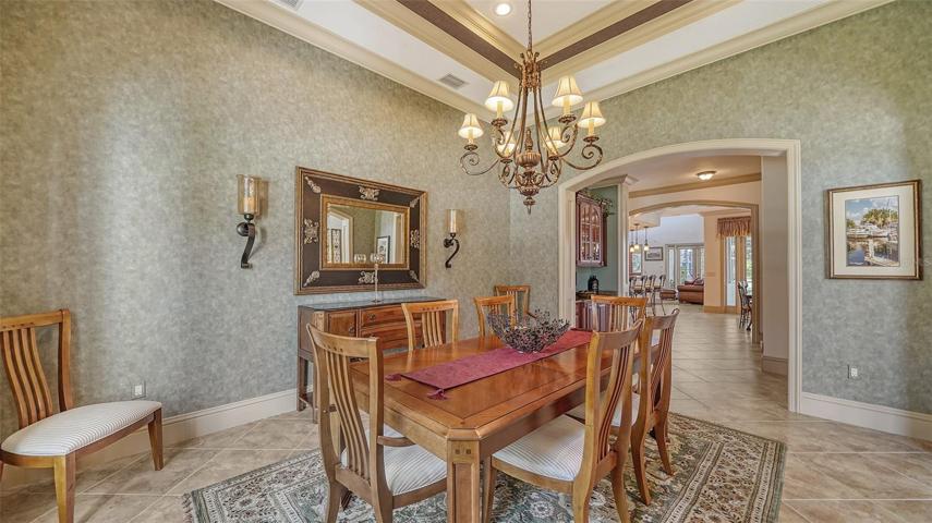 The dining room  features a custom tray ceiling, designer chandelier, and convenient butler's pantry.