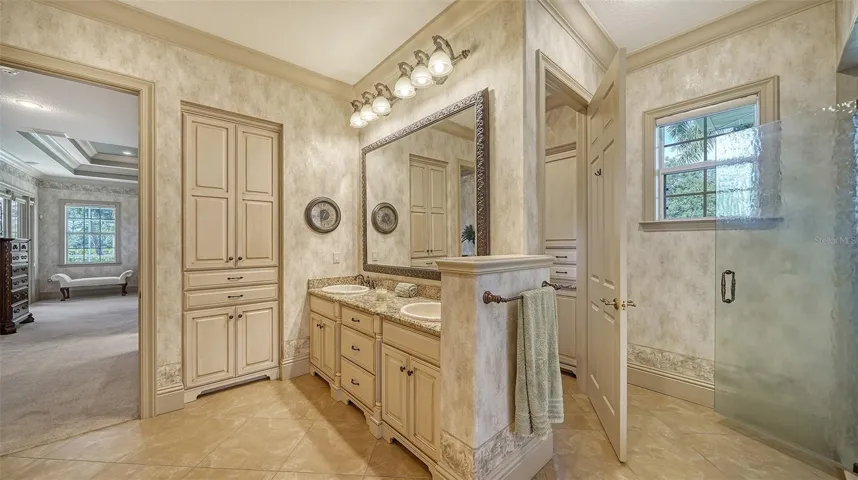 The large first floor owner's suite bathroom with luxe tile and glass spa-like bath.