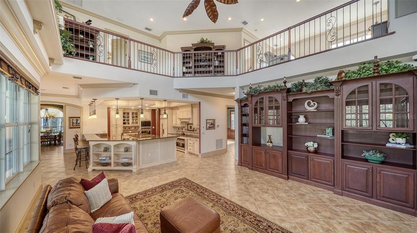 The vast Great Room basks in natural light from above topped by a 22’ ceiling, glass front, solid wood built ins, and French doors leading to more outdoor space.