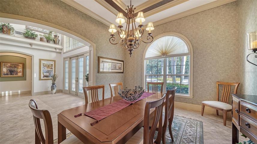 The stately dining room anchored off the foyer features a custom tray ceiling, designer chandelier, and convenient butler's pantry.